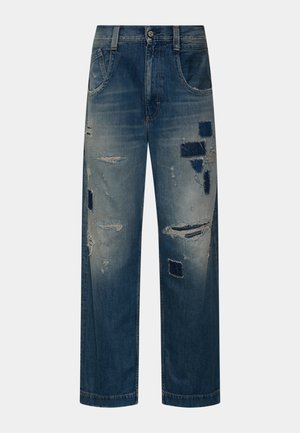 Modré džínové kalhoty s volným střihem, obsahující roztrhané oblasti a tmavé záplaty na předních stehnech a kolenou.