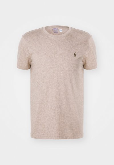 Beige t-skjorte med korte ermer laget av mykt stoff, med rund hals og en liten mørk logo på venstre bryst.