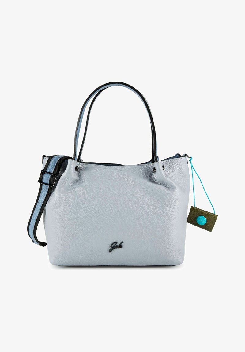Sac à main en cuir gris clair avec deux poignées bordées de noir, une bandoulière réglable et une petite étiquette attachée avec un cordon bleu.