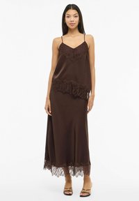 Brūna satīna slip kleita ar mežģīņu detaļām apakšmalā un ķermeņa daļā, ar plānām regulējamām spageti lencēm un plūstošu dizainu.