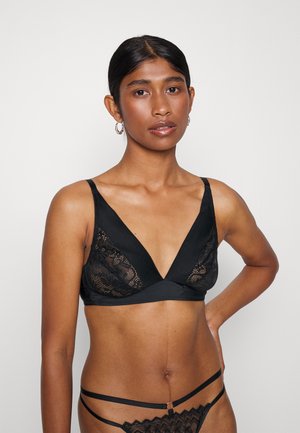 Black bralette with a deep V-neck design, featuring lace panels and a smooth underband. Adjustable straps; lightweight fabric adds texture.