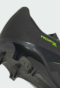 Czarny but piłkarski z neonkowożółtym napisem "PREDATOR EST. 1994", teksturowanym cholewką i czarnymi wtopionymi korkami w podeszwie.