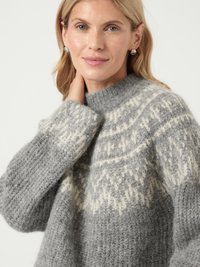 Grijs wollen sweater met een hoge hals, met een witte geometrische patroon langs de schouders en zachte, textuurstof.