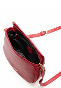 Bolso de hombro de cuero rojo con un acabado texturizado, cierre de cremallera y correa ajustable. El interior está forrado con tela negra y tiene un bolsillo.