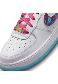 Weiße Sneaker mit pinken Schnürsenkeln, goldener Schnürsenkel-Tag, blauem gemustertem Logo und hellblauer durchsichtiger Sohle.