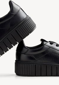 Svarta lädersneakers med platå, ribbad sula, rund tå och snörning fram. Slät yta med diskreta sömnadsdetaljer.