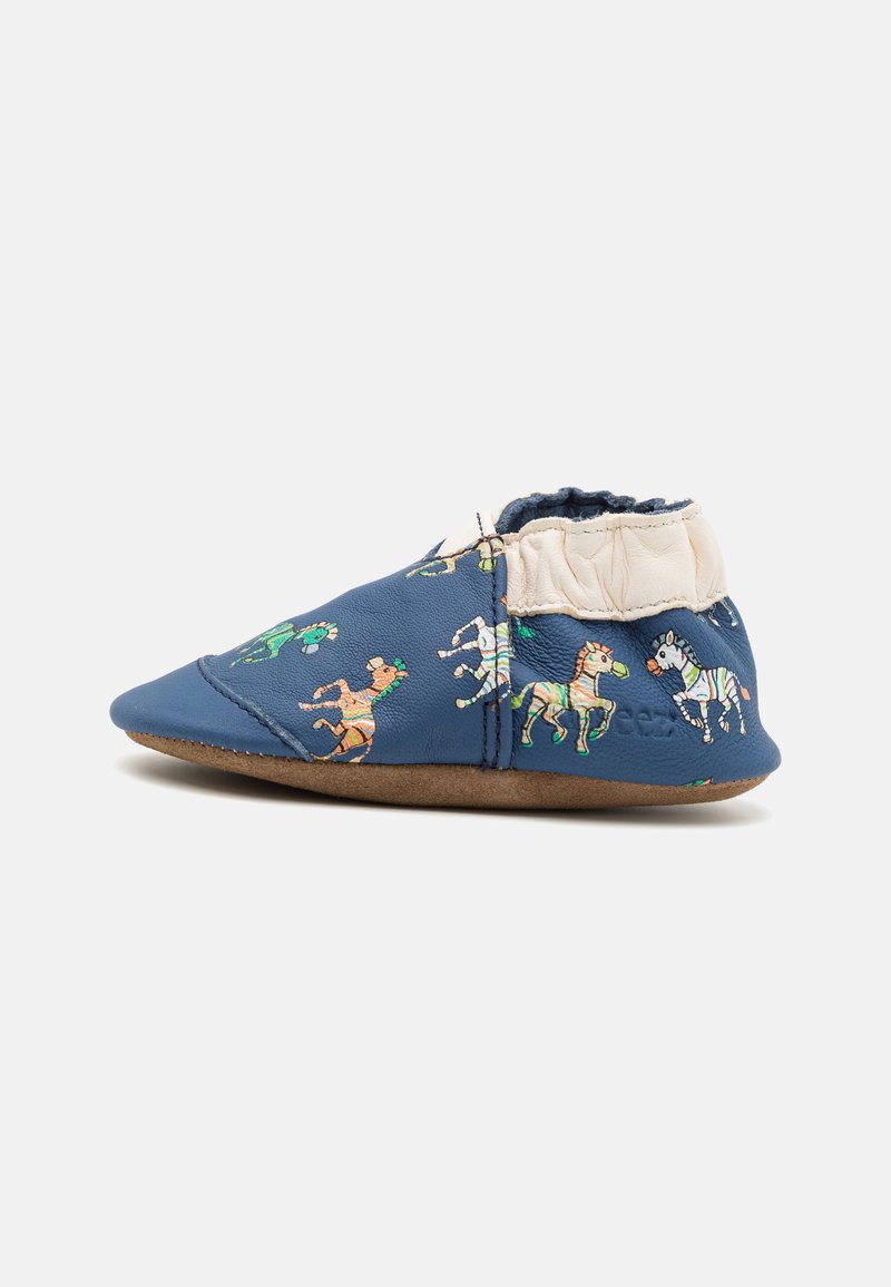 Chaussure en cuir bleu doux pour enfant ornée de motifs colorés de chevaux. Cheville élastiquée pour un bon maintien, avec une semelle en daim marron flexible.