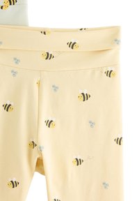 Κίτρινες κολάν με επαναλαμβανόμενο σχέδιο μελισσών και λουλουδιών, κατασκευασμένες από απαλό ύφασμα με ελαστική μέση για άνεση.