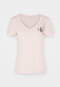 Světle růžové dámské tričko s výstřihem do V vyrobené z bavlny. Má krátké rukávy a malé černé logo "CK" na levé části hrudi.
