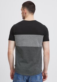 Camiseta negra y gris de manga corta; presenta una sección superior negra sólida, un medio texturizado en gris y una sección inferior a rayas.
