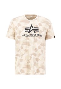Beige bomulls-t-shirt med abstrakt ljusbrun camouflagemönster. Har en svart "Alpha Industries"-logotyp på bröstet. Korta ärmar, rundad halsringning.
