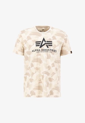 Beige Baumwoll-T-Shirt mit abstraktem hellbraunem Camouflage-Muster. Mit schwarzem "Alpha Industries"-Logo auf der Brust. Kurze Ärmel, Rundhalsausschnitt.