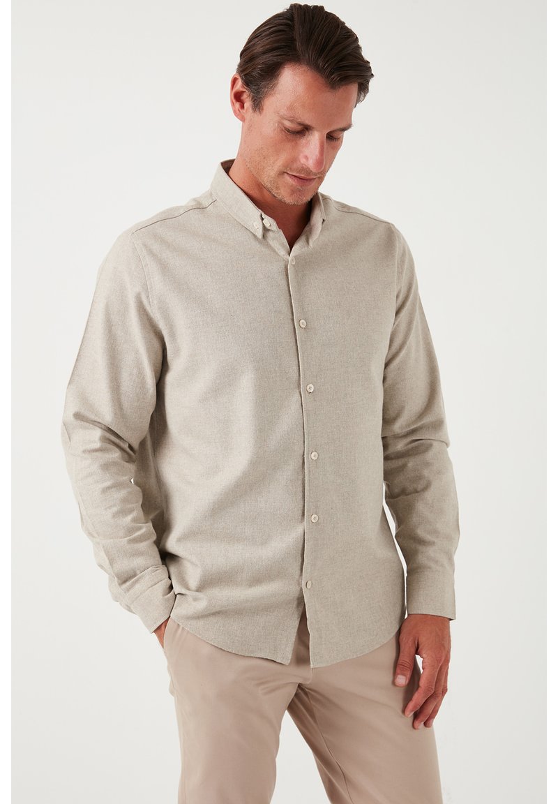 Camicia beige con bottoni realizzata in tessuto morbido, caratterizzata da un colletto, maniche lunghe e una superficie leggermente texture. Design semplice e classico.