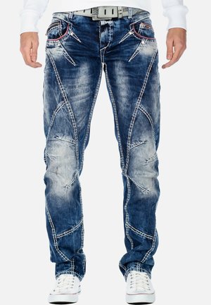 Jeans in denim blu con toppe strappate, cuciture bianche a contrasto e un design affusolato. Presentano tasche anteriori con cuciture di accento.