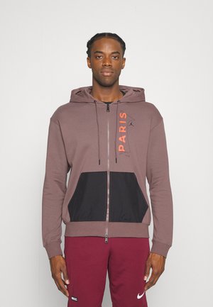 Marsala hoodie med sorte detaljer og kengurulomme, med teksten "PARIS" i orange, lynlås lukning og snoretræk. Blød stoftekstur.