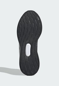 Schwarze Gummisohle mit strukturiertem Profil; die Seite weist weiße Akzente auf. Entworfen für Grip und Langlebigkeit.