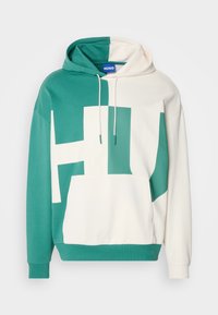Mikina s kapucí značky Hugo s rozděleným designem v tyrkysové a krémové barvě, s velkým grafickým motivem "HU", šňůrkami na stažení a klokáním kapsou.