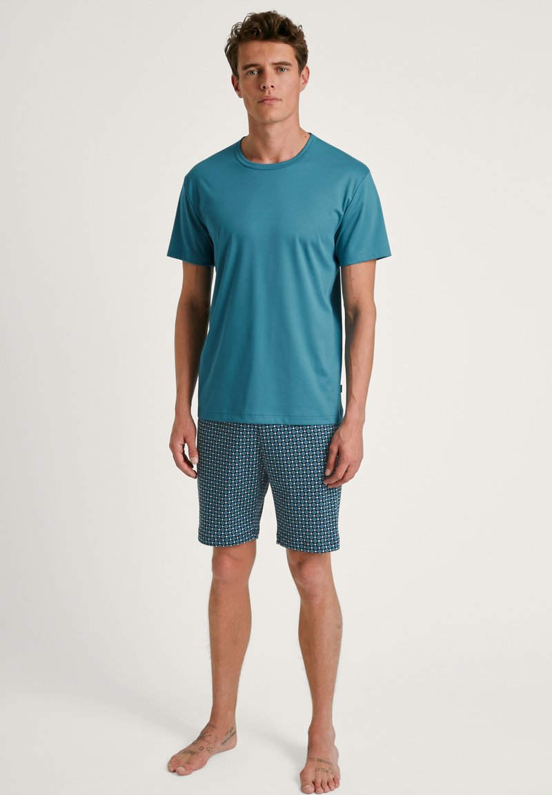 Korte mouw teal t-shirt gecombineerd met gestreepte blauwe shorts met ronde patronen, gemaakt van lichtgewicht stof, geschikt voor casual wear.