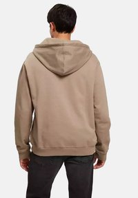 Kaptur w kolorze jasnobrązowym z mieszanki bawełny, o luźnym kroju, z prążkowanymi mankietami i przyszywaną kieszenią kangurką z przodu.