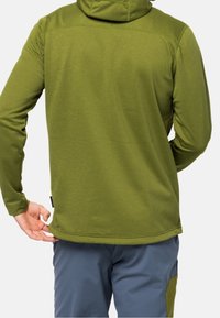 Zelená fleecová mikina s dlouhými rukávy, vysokým límcem a volným střihem. Jednoduché švy a rovný spodní lem doplňují design.