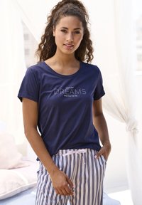 Navy blue short-sleeve T-shirt with the text "follow your DREAMS they know the way" in white embroidery, paired with striped pajama pants.