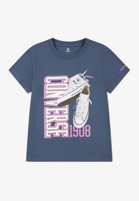 Camiseta de algodón azul marino con un gráfico de zapatillas Converse blancas y el texto en negrita "CONVERSE 1908" en rosa y blanco. Mangas cortas.