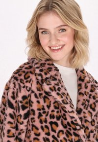 Abrigo de pelo sintético en rosa con un patrón de leopardo en negro y marrón. Presenta un cuello con muescas y un acabado suave y texturizado.