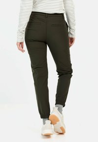 Olivgrüne Jogginghosen mit elastischem Bund und Bündchen, aus einem glatten, leichten Material. Zwei sichtbare Gesäßtaschen.