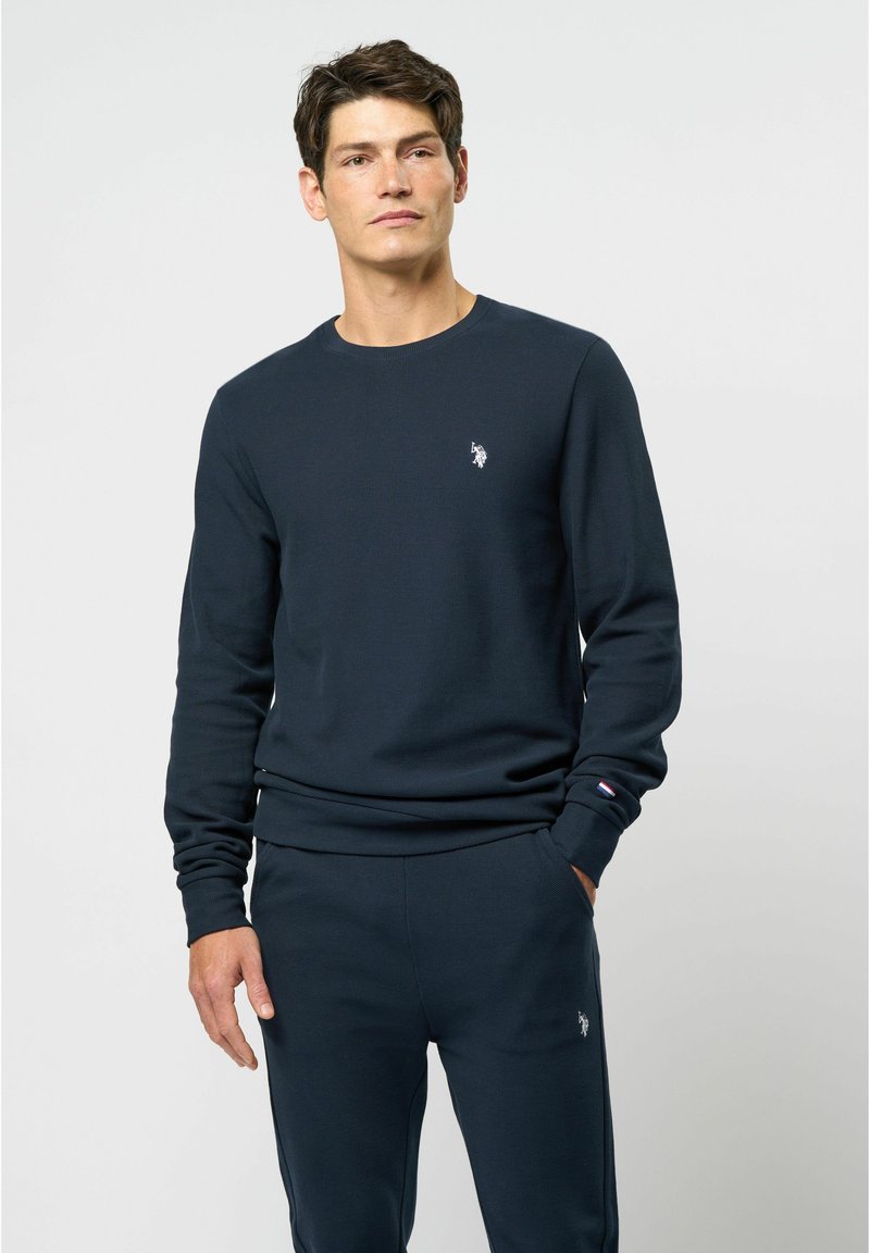 Marine crewneck sweatshirt gemaakt van textuurstof, met een klein geborduurd logo op de borst en geribbelde manchetten. Gecombineerd met bijpassende broek.