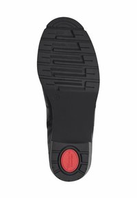 Suela de zapato de goma negra con patrón de textura, que presenta un acento rojo etiquetado como "COMFORT" y diseño de tacón redondeado.