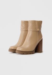 Bottes beiges mi-mollet en cuir lisse avec un dessus texturé, dotées d'un bout rond, d'un talon épais et d'une semelle à relief.