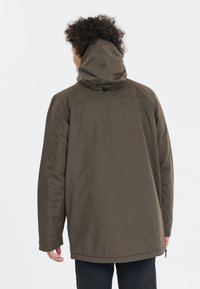 Ruskea huppari, jossa kestävä ulkopinta, rento malli, pitkät hihat ja säädettävä helma, nähtynä takaa.