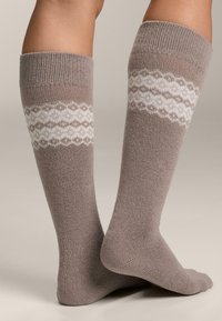 Podkolienky v taupe farbe s textúrovaným pleteným dizajnom a bielym vzorovaným pásom okolo strednej časti lýtka, so zobrazujúcim geometrický motív.