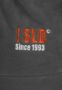 Gray fleece fabric featuring embroidered text: "! SLD" in orange and "Since 1993" in white, with a rounded edge at the bottom.