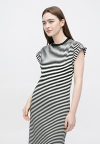 Zwart-wit gestreepte jurk met een geribbelde textuur, korte opgerolde mouwen en een ronde halslijn, nauwsluitend op het lichaam.