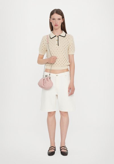 Knit beige polo with black collar, short sleeves, and openwork pattern; white denim shorts; pink pouch bag with chain strap; black flats.