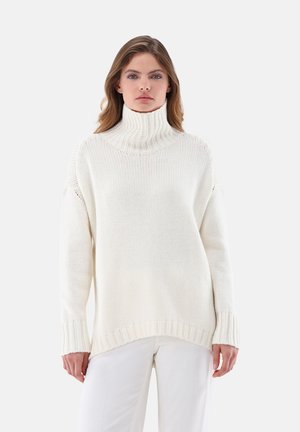 Chunky knit turtleneck sweater in cream, featuring ribbed cuffs and hem, with a relaxed fit and side slits for ease of movement.