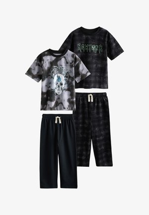 Dos conjuntos de camisetas de manga corta en negro y gris y pantalones con cordón; una camiseta tiene un diseño de calavera, la otra dice New York.