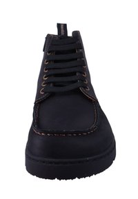 Zapato de cuero negro con punta redondeada, que presenta cordones negros, ojetes de bronce y costuras marrones en contraste a lo largo de los bordes.