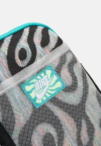 Sporttáska sarok, multiszínű örvénymintával, türkiz kiegészítővel és rávarrt türkiz és sárga Nike logóval.