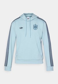 Light blue hooded sweatshirt with navy stripes, front pocket, and embroidered Spanish crest on the chest. Features Adidas logo on the side.