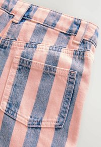 Un tejido de mezclilla a rayas rosa y azul presenta un bolsillo trasero y detalles cosidos, mostrando una mezcla de colores y texturas.