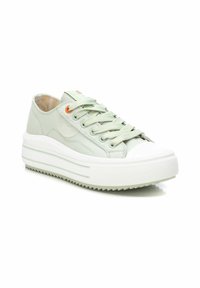 Zapatillas de lona verdes con una suela blanca gruesa, punta redonda y suela de goma texturizada; cuentan con acentos en naranja y crema en los cordones.