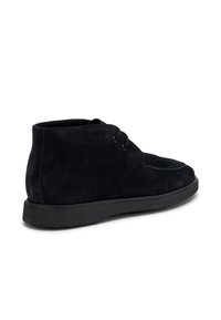Botas de tobillo de ante negro con punta redonda, diseño de cordones y superficie texturizada. Cuentan con una suela de goma plana para mayor comodidad.