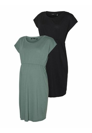 Grünes, kurzärmliges Schwangerschafts Kleid mit tailliertem Oberteil und lockerem Rock, gefertigt aus weichem Stoff. Getragen mit weißen Sneakern.