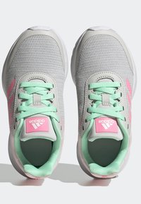 Scarpe da ginnastica in mesh grigio con lacci e dettagli verde menta; presenta un logo rosa sulla linguetta e strisce laterali.