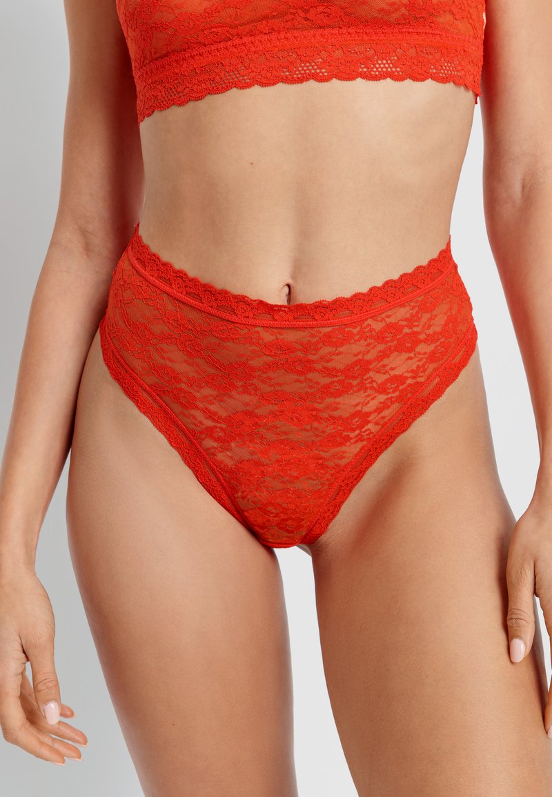 Red lace high-waisted briefs with scalloped edges, featuring a floral pattern and a sheer texture, offering a delicate and feminine look.
