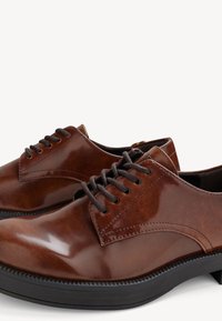 Zapatos de cuero marrón con un acabado brillante, diseño con cordones, punta redonda y suela de goma negra contrastante. Presentan acentos cosidos.