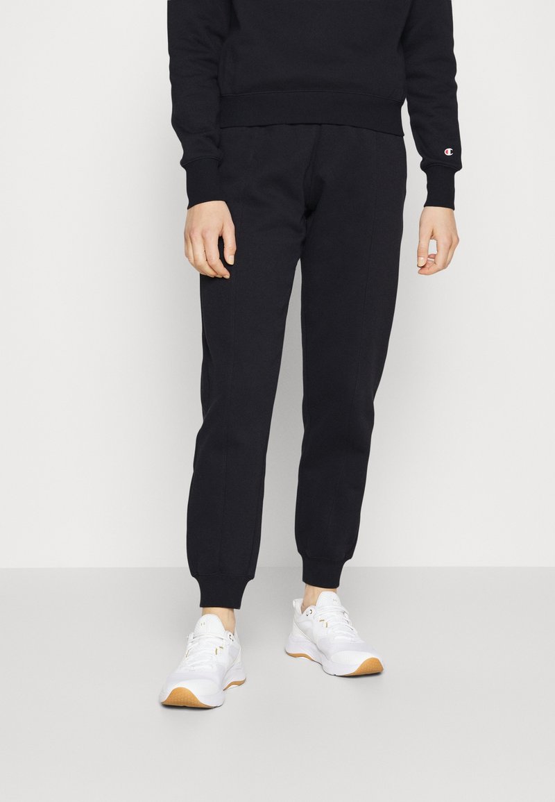 Svarta joggers i bomullsblandning med elastiska muddarna, med sidosömmar. Matchas med vita sportskor med bruna detaljer.