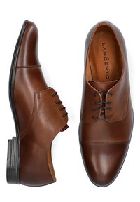 Brązowe skórzane buty wizytowe z noskiem typu cap toe, gładką fakturą i kontrastującymi czarnymi sznurówkami. Solidny obcas oraz smukły, elegancki kształt.